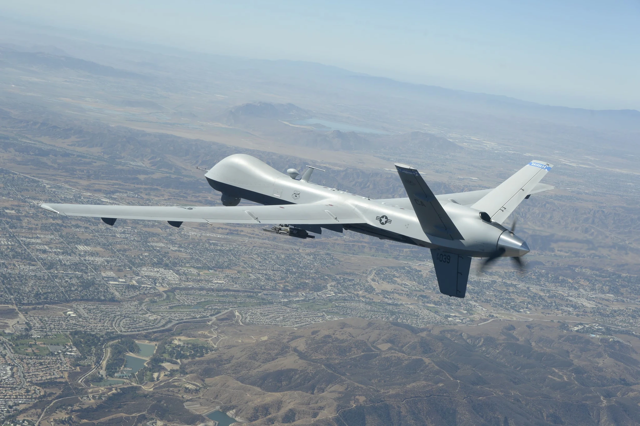An uncrewed fixed-wing aircraft flying above a mountainous landscape.